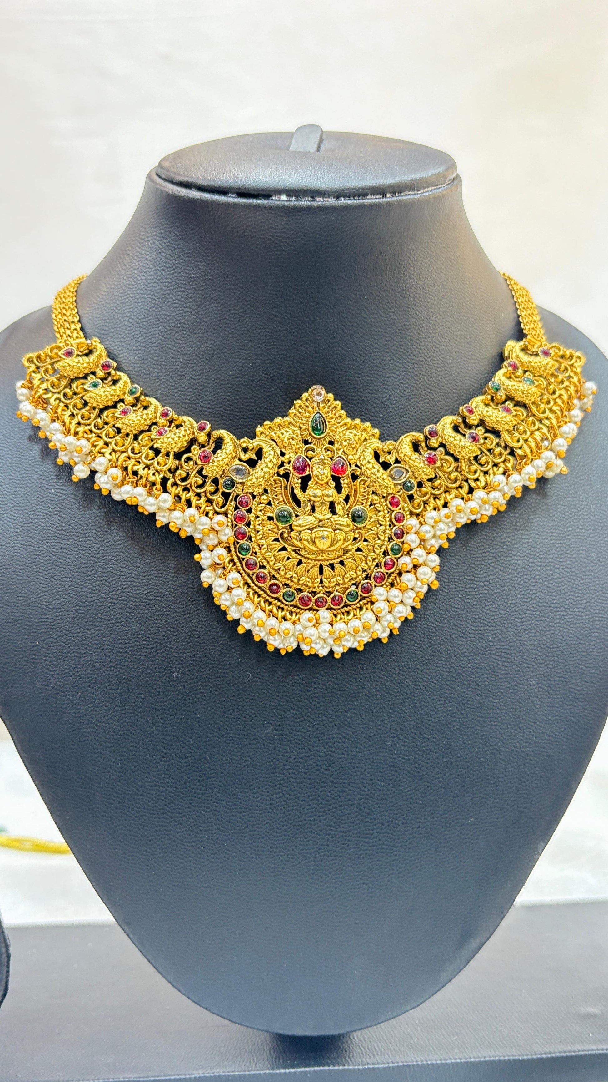 Gold necklace with intricate designs on a mannequin bust