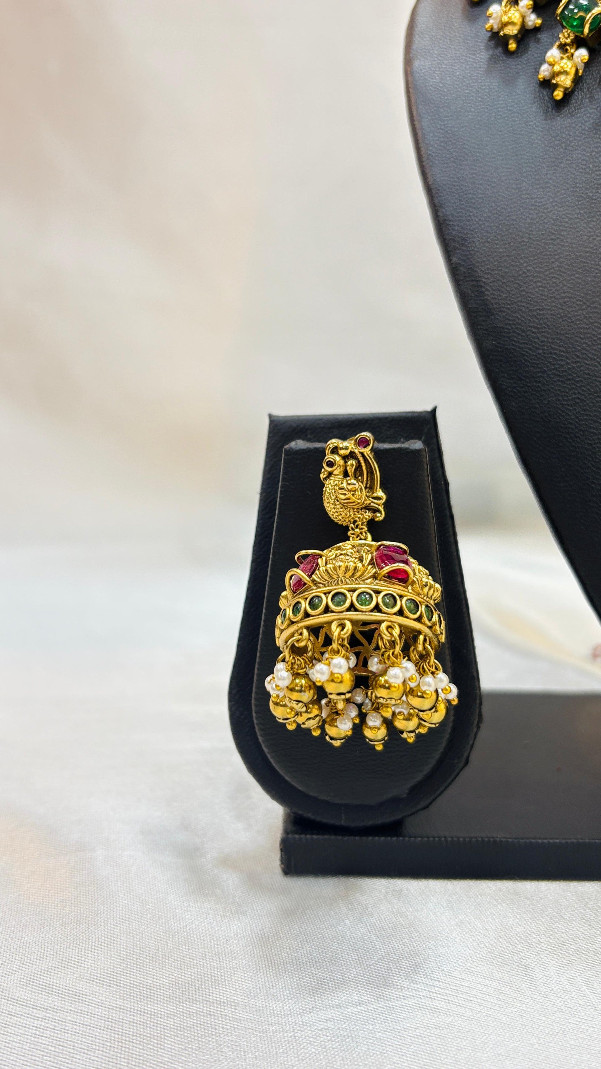 Gold and pearl earring on a black stand with a blurred background