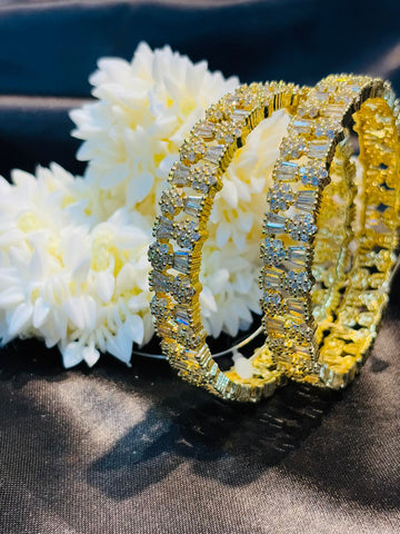 Gold and diamond bracelet on a dark surface with white flowers