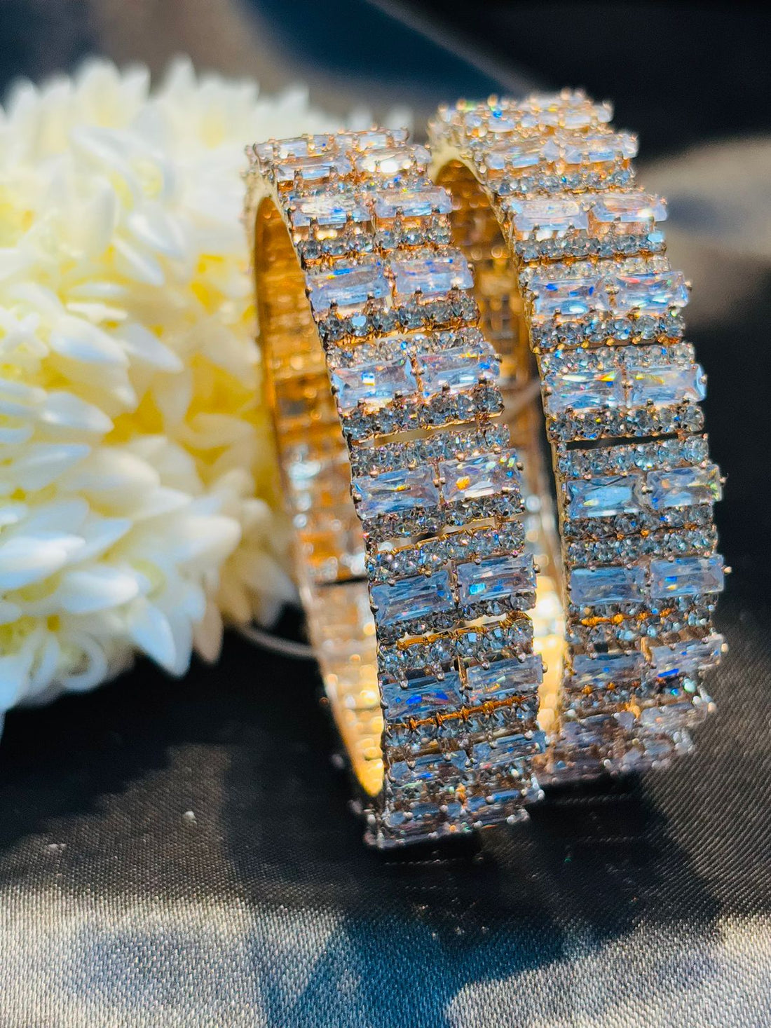 Gold and diamond bracelet on a white flower with a dark background