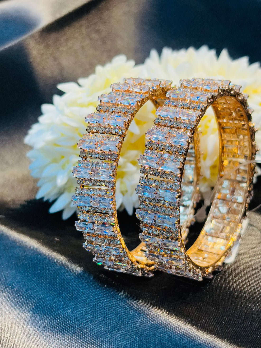 Gold and diamond bracelet on a white flower with a dark background