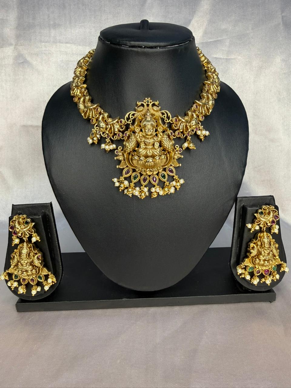 Gold necklace with intricate design on a black mannequin