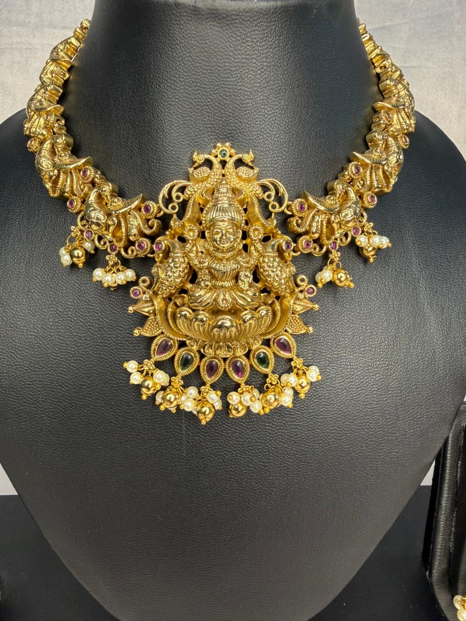 Gold necklace with intricate design on a black mannequin