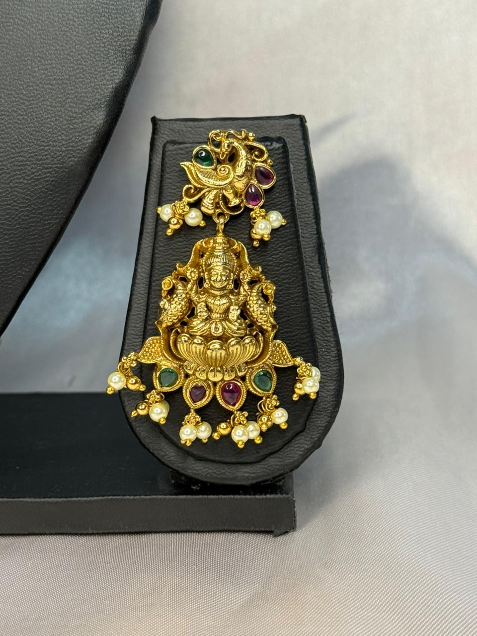Gold jewelry piece with gemstones on a black stand