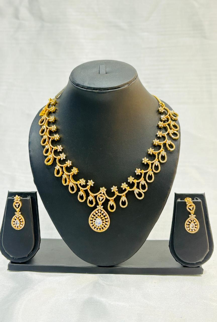 Gold necklace and earrings set on a black mannequin bust against a white background