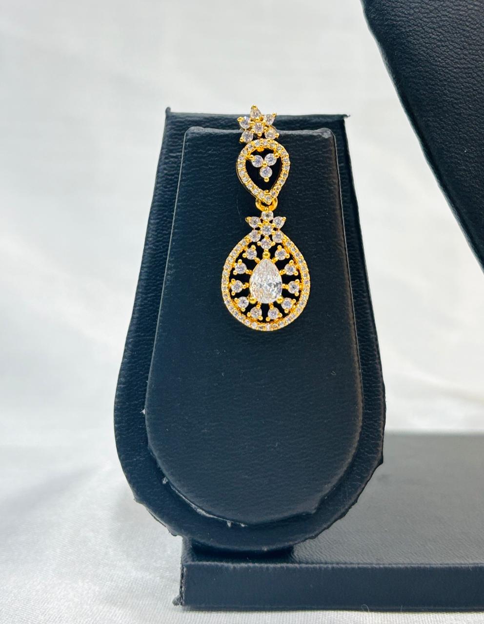 Gold and diamond earring on a black display stand against a white background