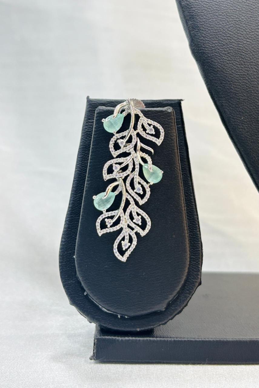 Jewelry box with a silver and green leaf-shaped earring on a white background