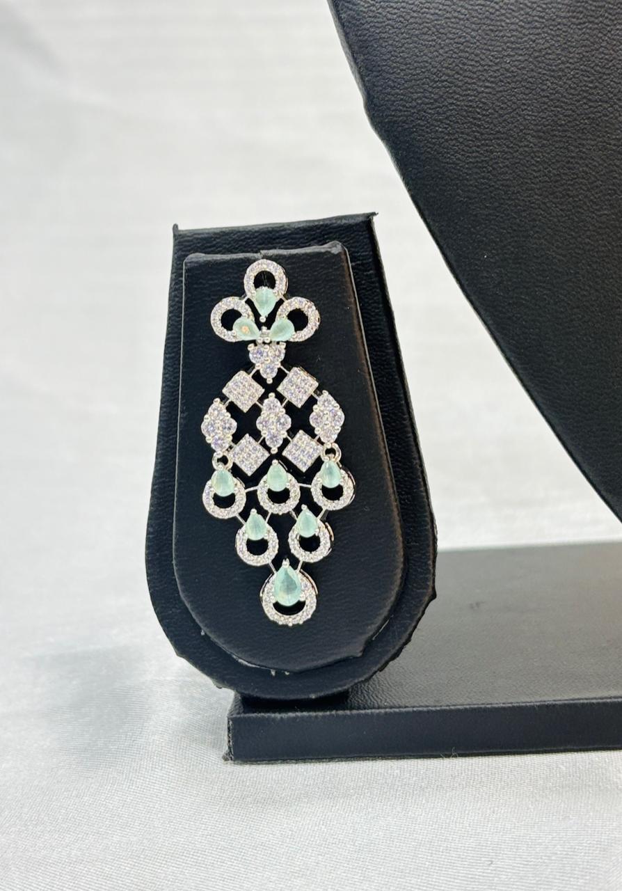 Diamond and emerald earring on a black stand with a white background
