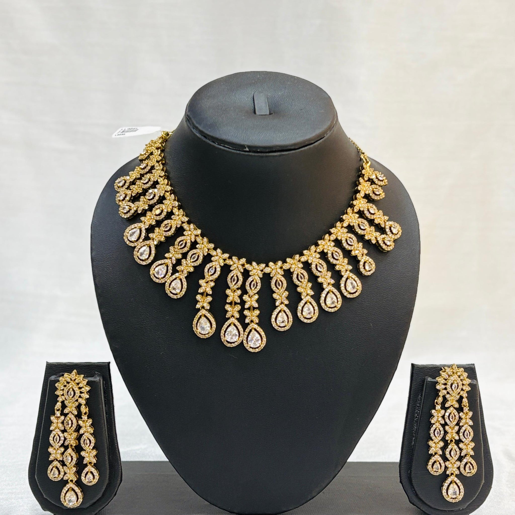 Gold necklace and earrings set on a black mannequin bust against a white background