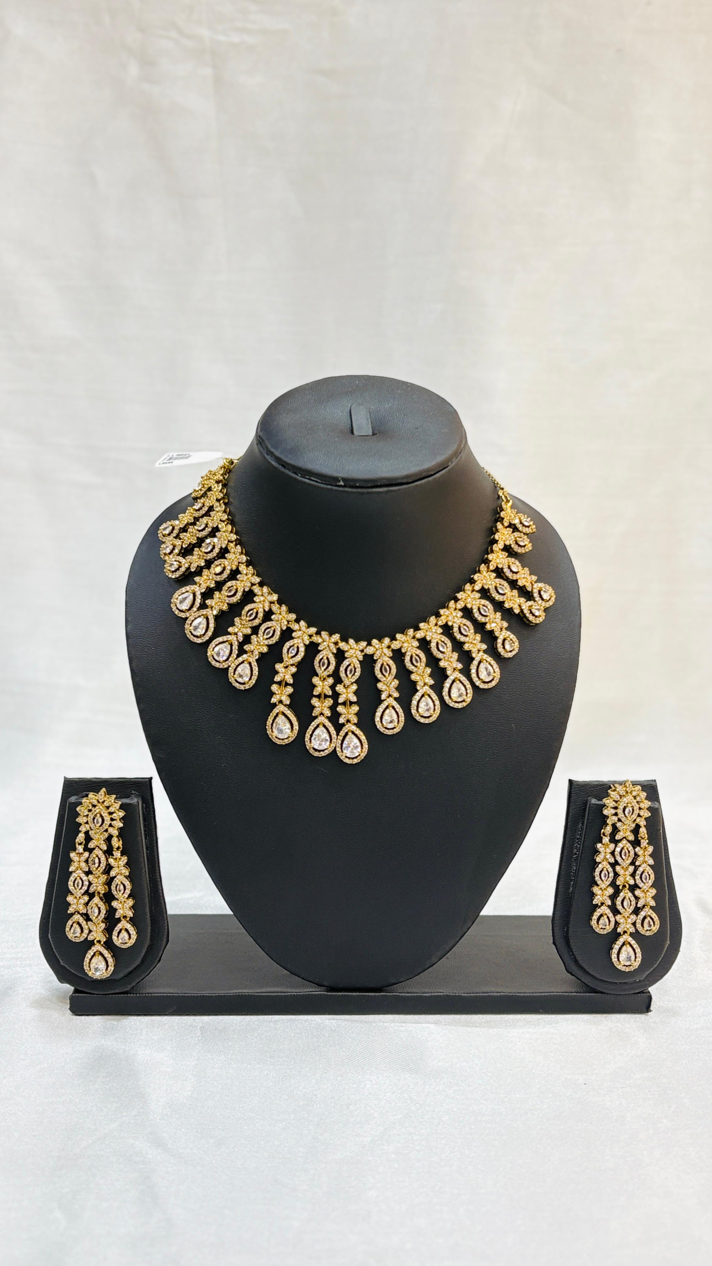 Gold necklace and earrings set on a black mannequin bust against a white background
