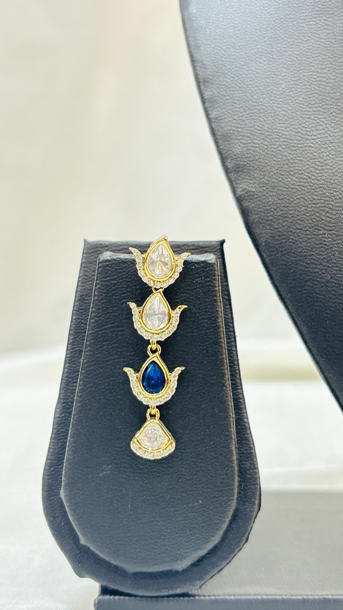 Gold necklace with matching earrings on a black mannequin bust against a white background