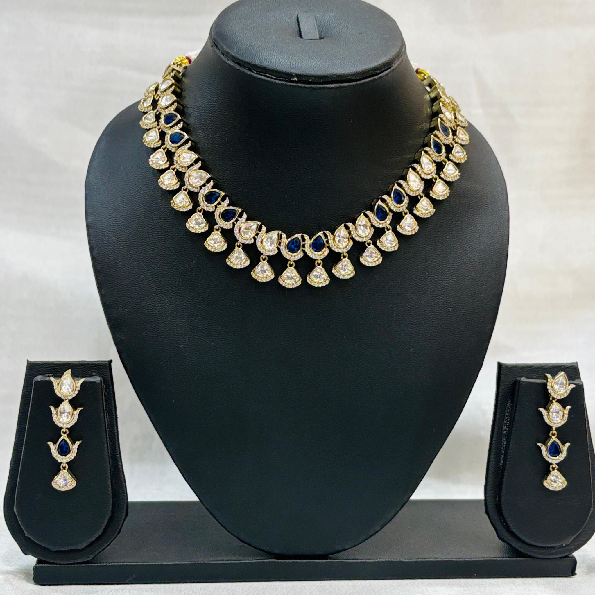 Gold necklace with matching earrings on a black mannequin bust against a white background