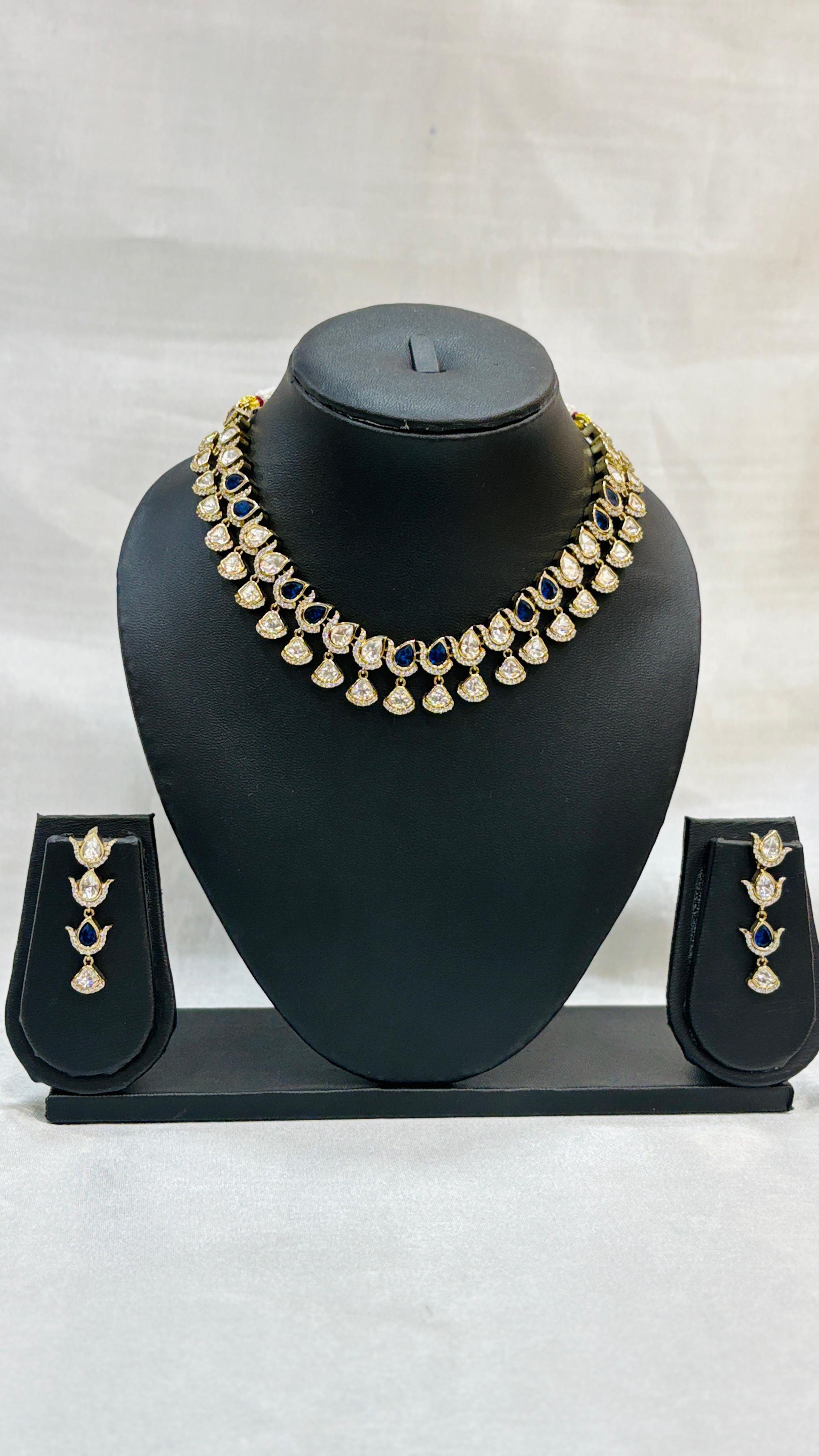 Gold necklace with matching earrings on a black mannequin bust against a white background