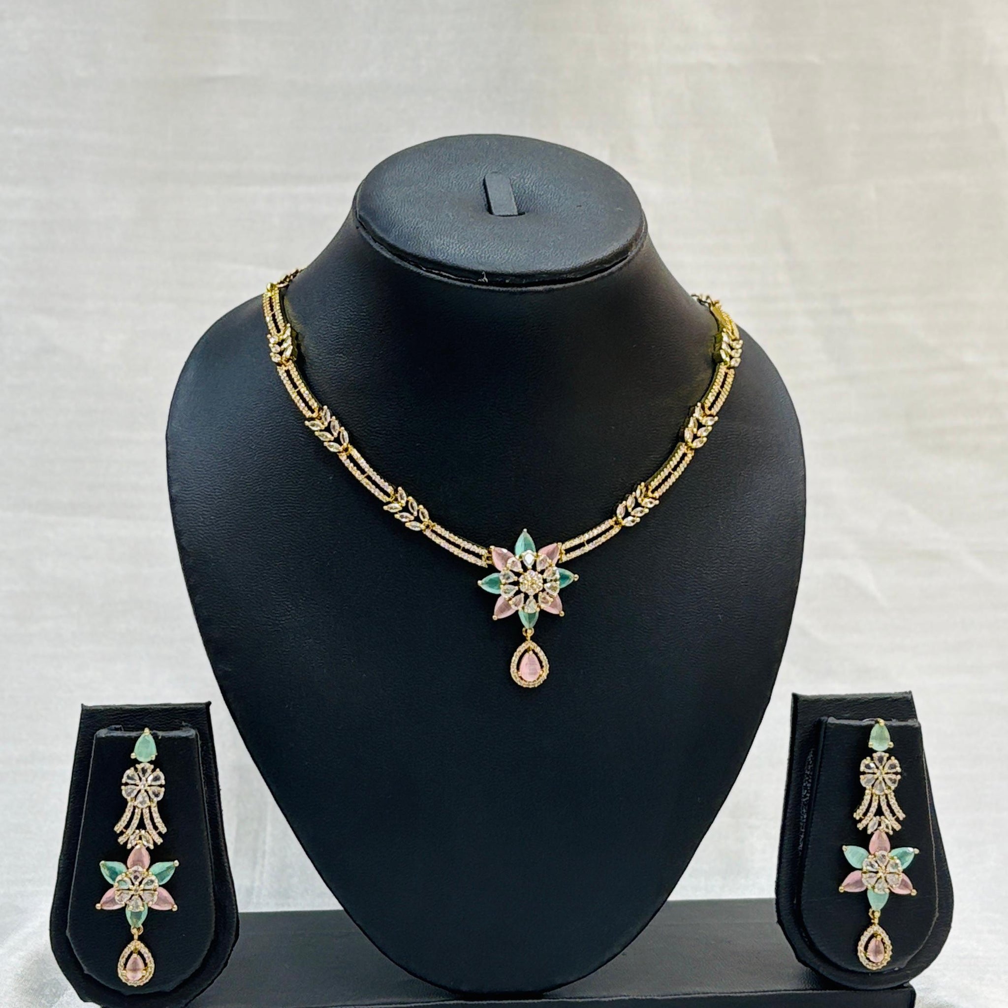 Jewelry set with necklace and earrings on a black mannequin bust against a white background