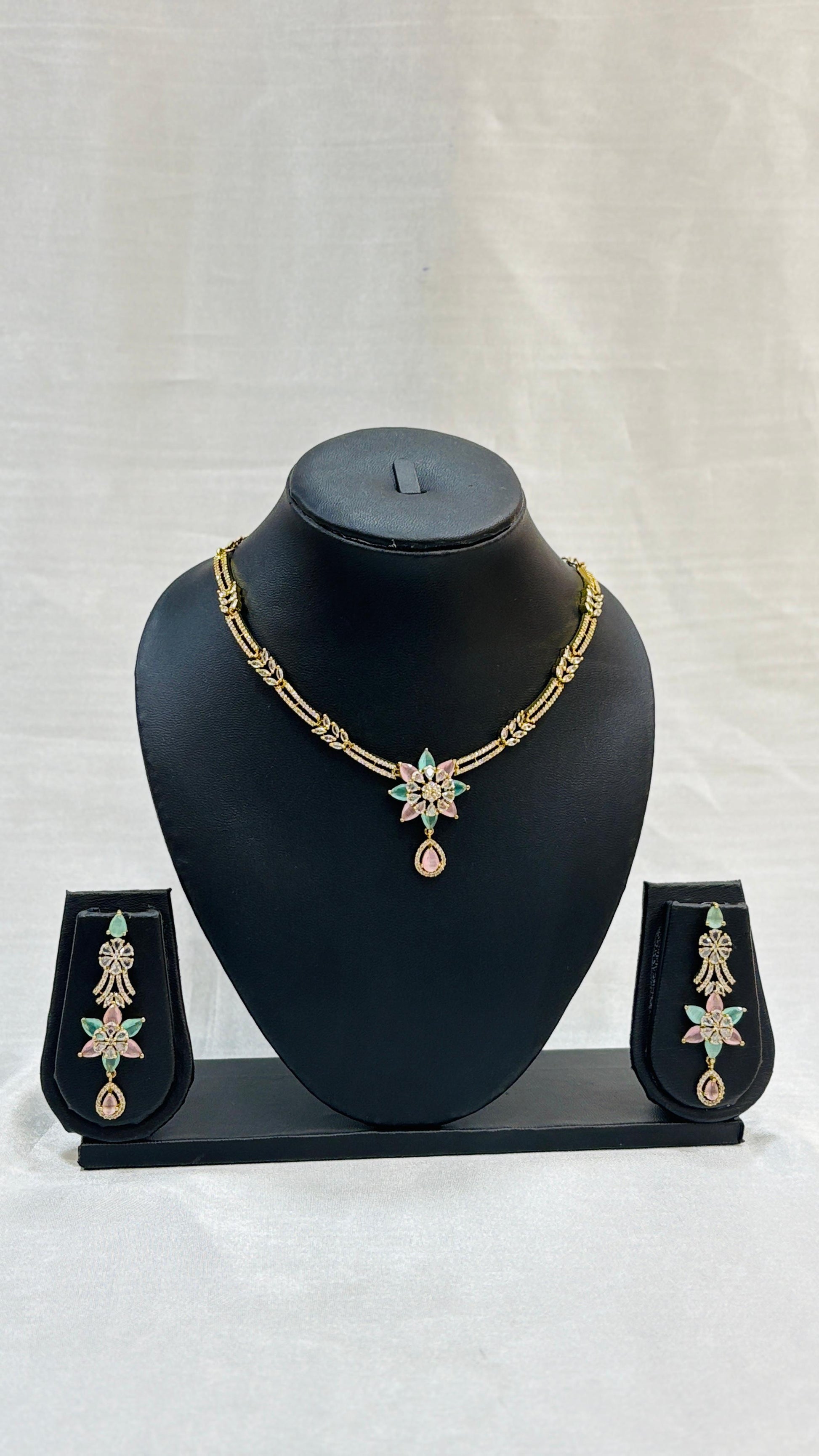 Jewelry set with necklace and earrings on a black mannequin bust against a white background