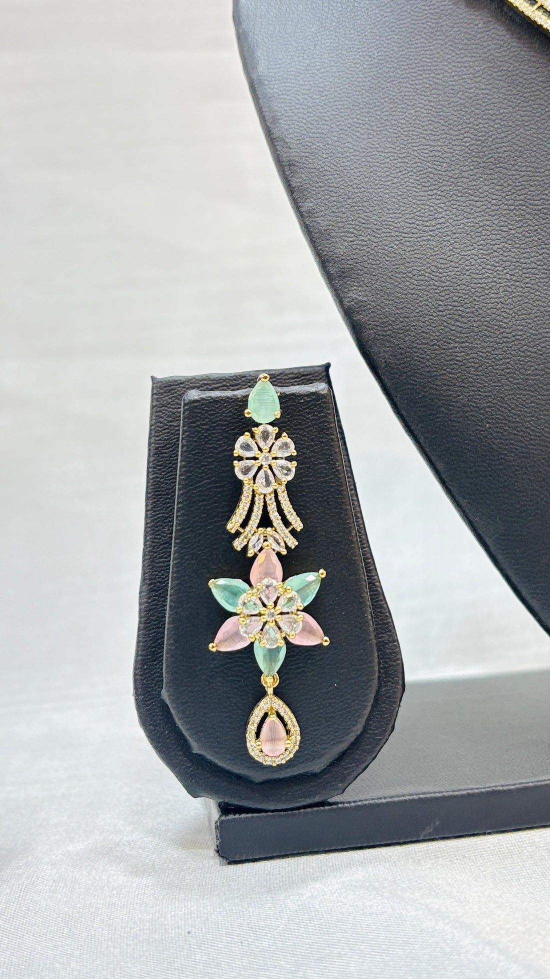 Jewelry set with necklace and earrings on a black mannequin bust against a white background