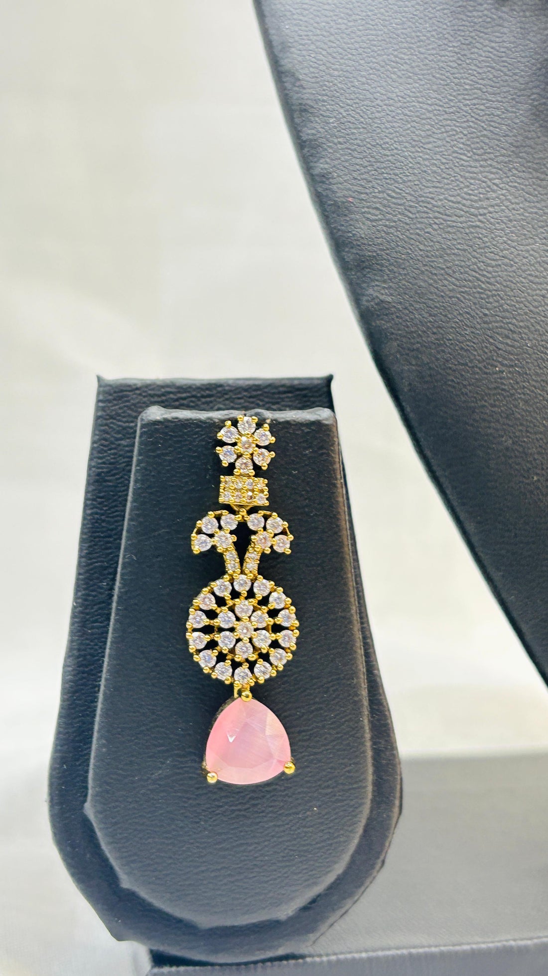 Jewelry set with necklace and earrings on a gray stand against a light background