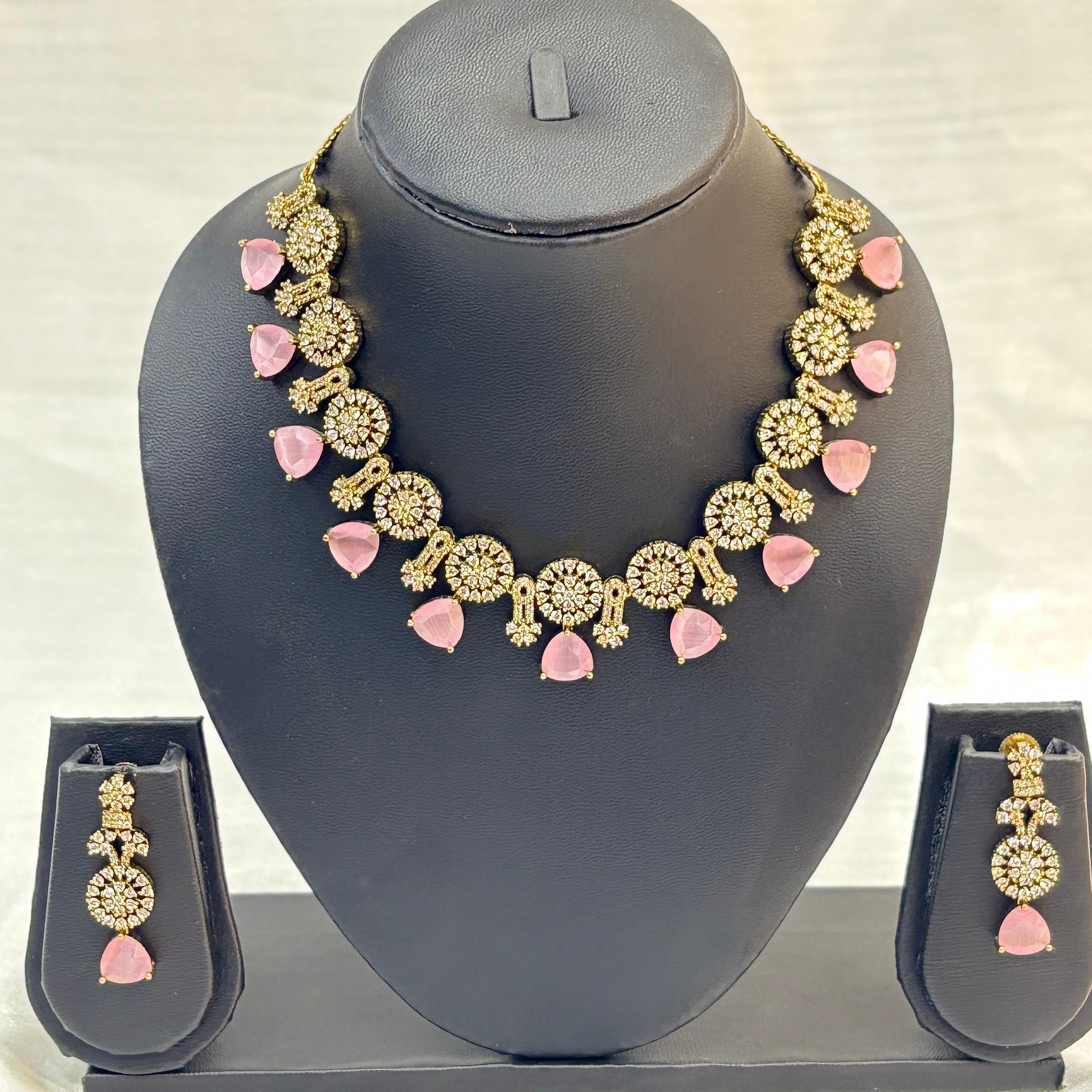 Jewelry set with necklace and earrings on a gray stand against a light background