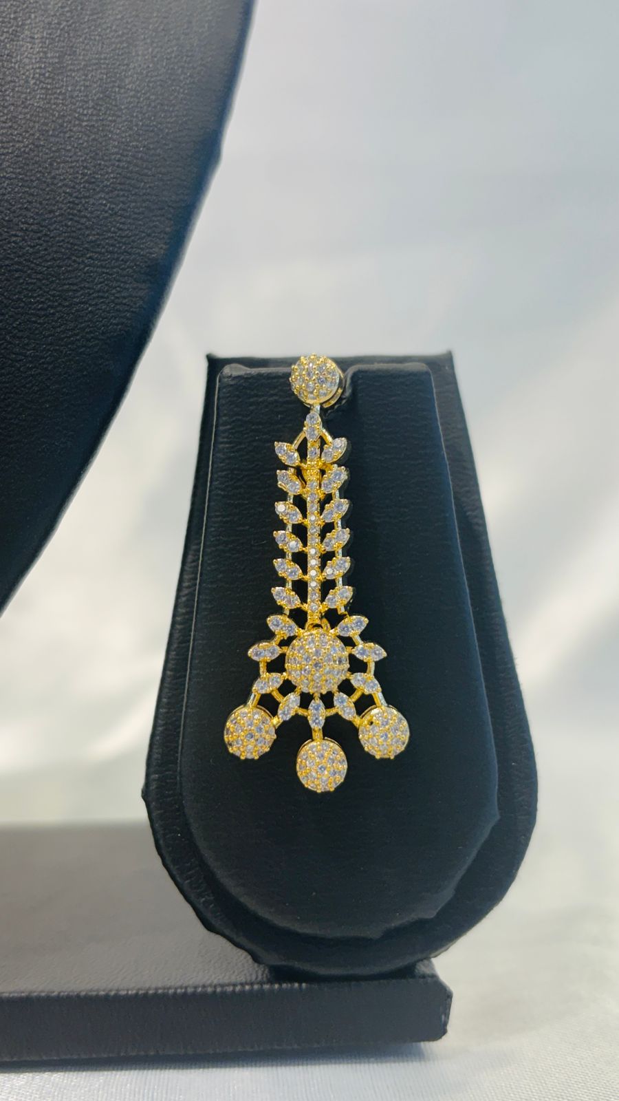 Gold necklace and earrings set on a black mannequin bust against a white background