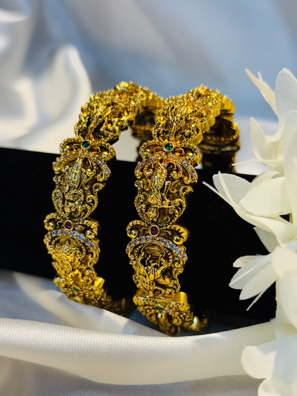 Gold bracelet with intricate design on a white fabric background