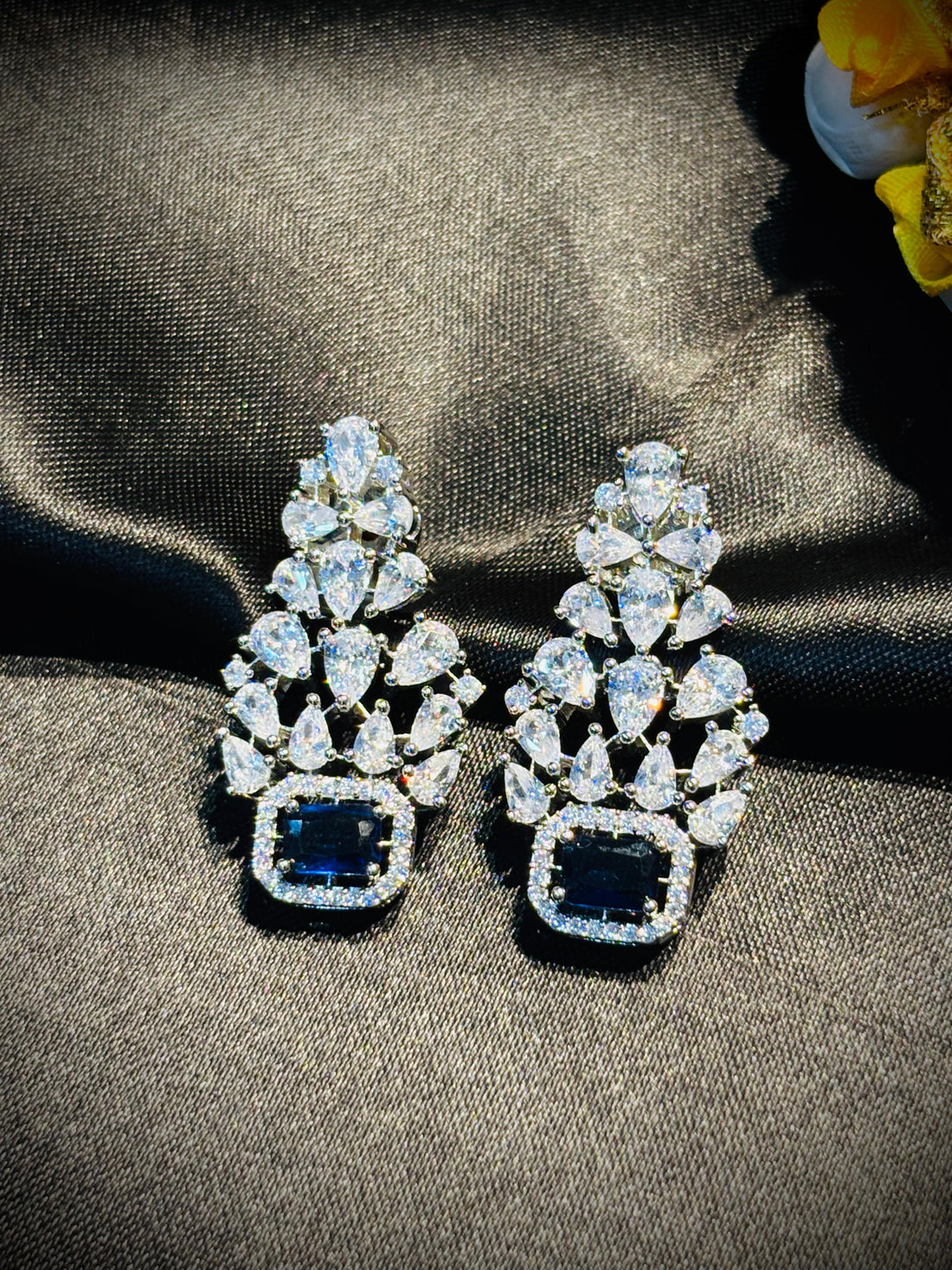 Diamond necklace and earrings on a dark fabric background with flowers.