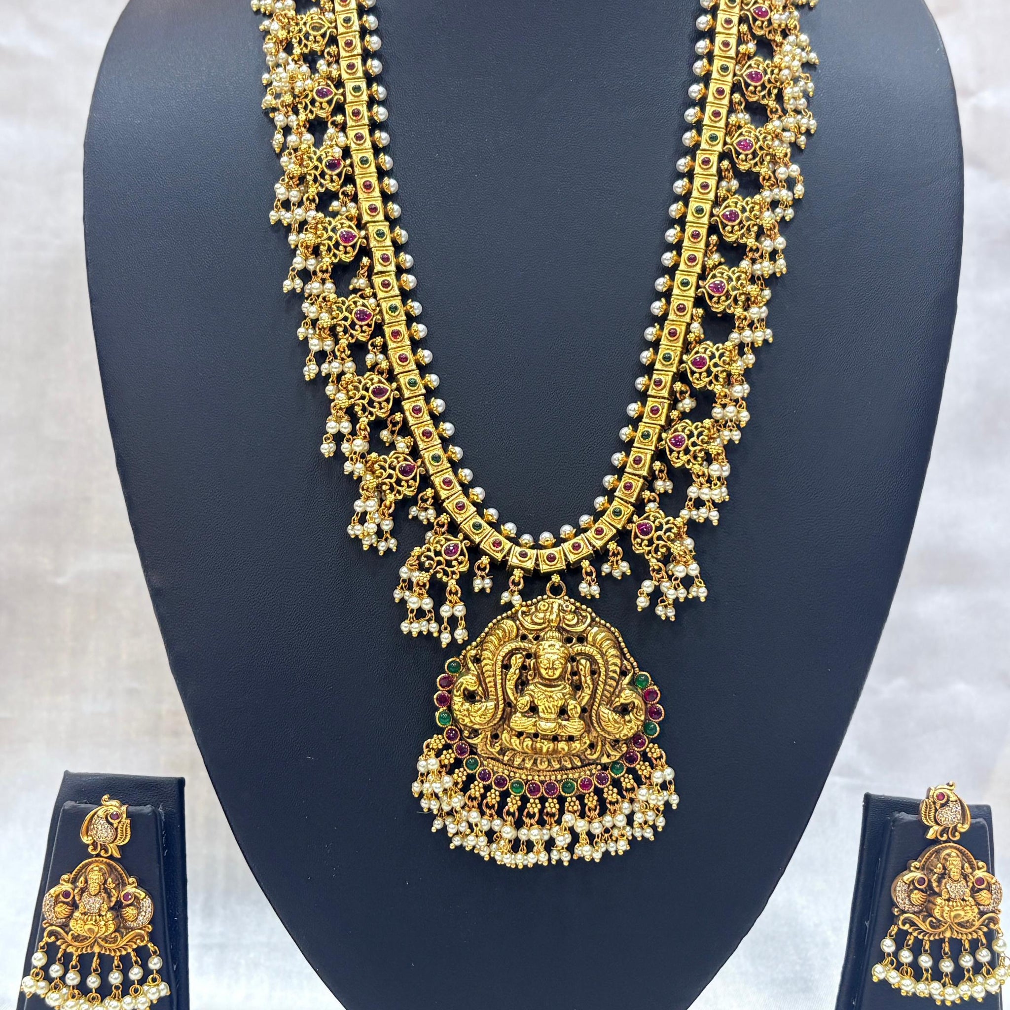 Gold necklace and earrings set on a black mannequin against a white background