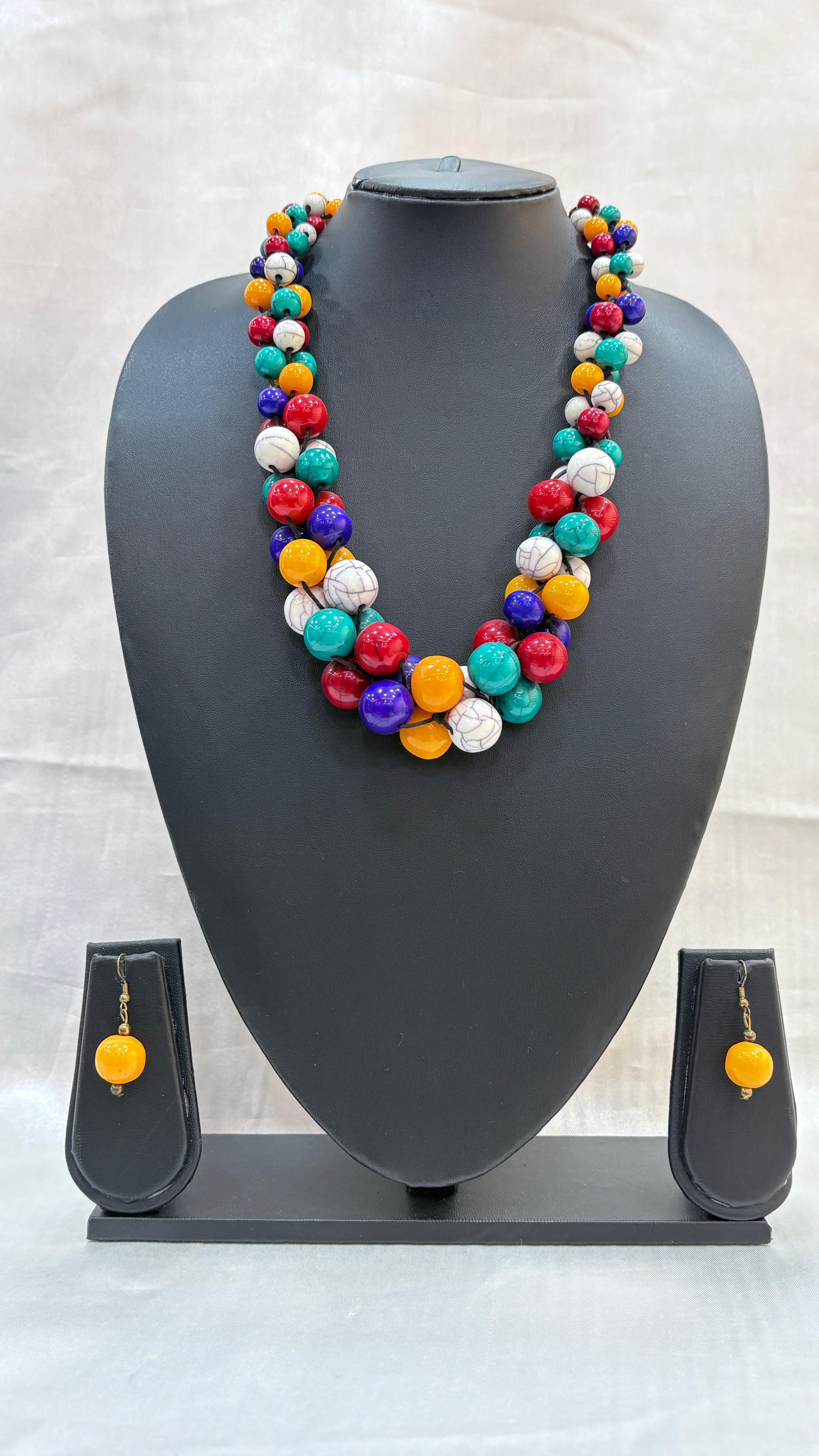 Colorful beaded necklace and earrings on a gray mannequin bust against a light background