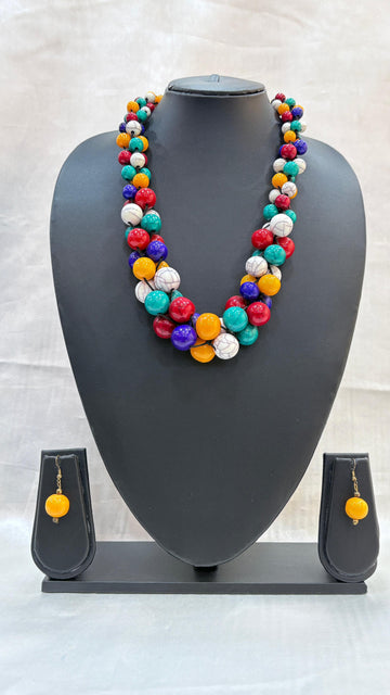 Colorful beaded necklace and earrings on a gray mannequin bust against a light background