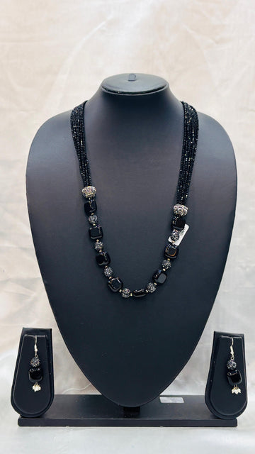 Black beaded necklace and earrings set on a black mannequin bust with a light gray background.