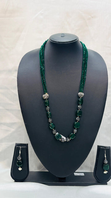 Green beaded necklace with matching earrings on a black mannequin bust against a white background