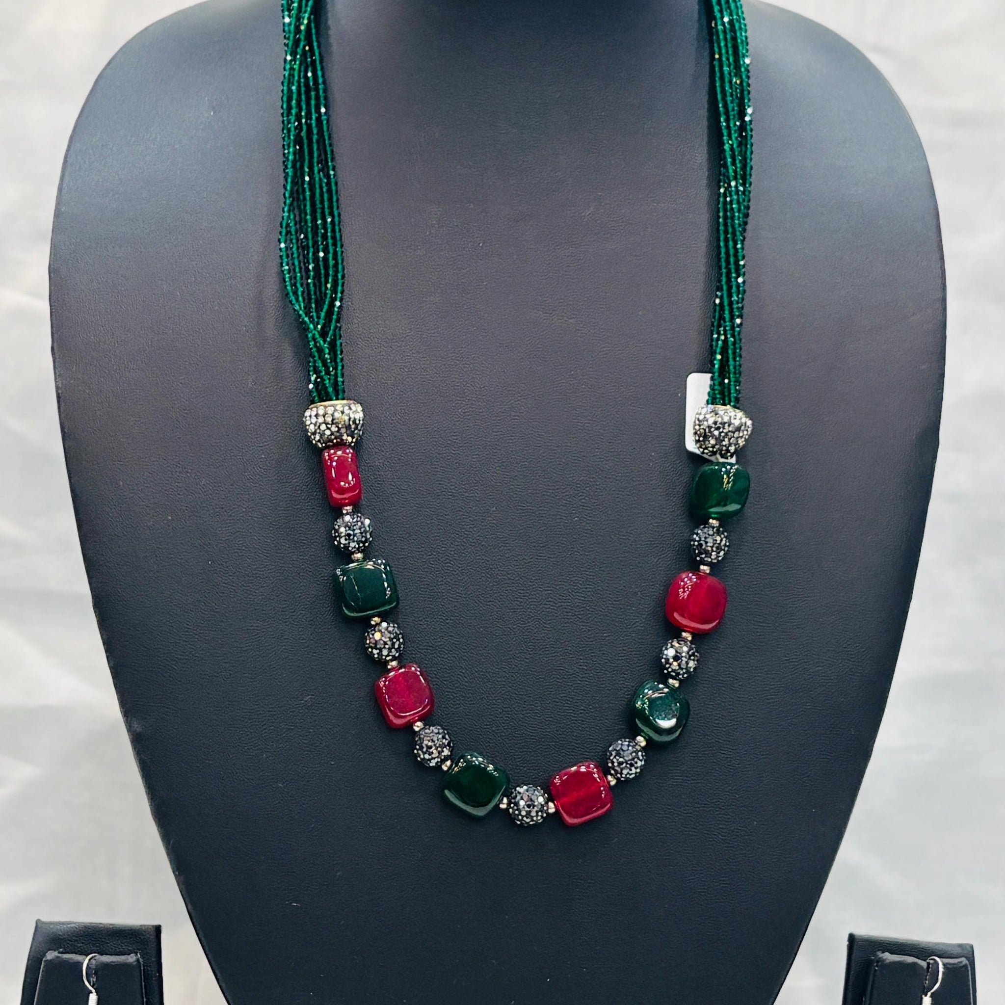 Jewelry set with necklace and earrings on a black mannequin bust against a white background