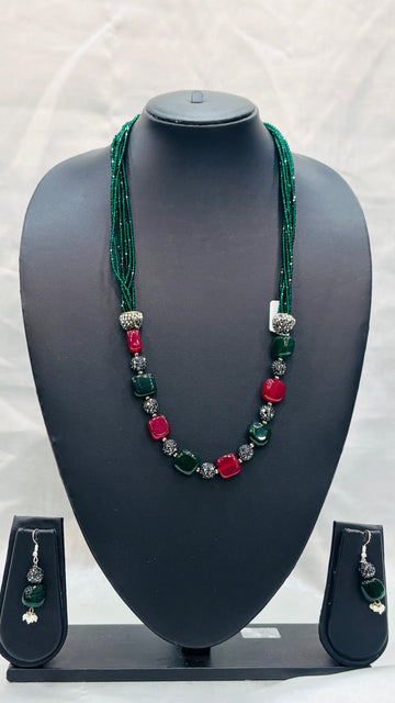 Jewelry set with necklace and earrings on a black mannequin bust against a white background