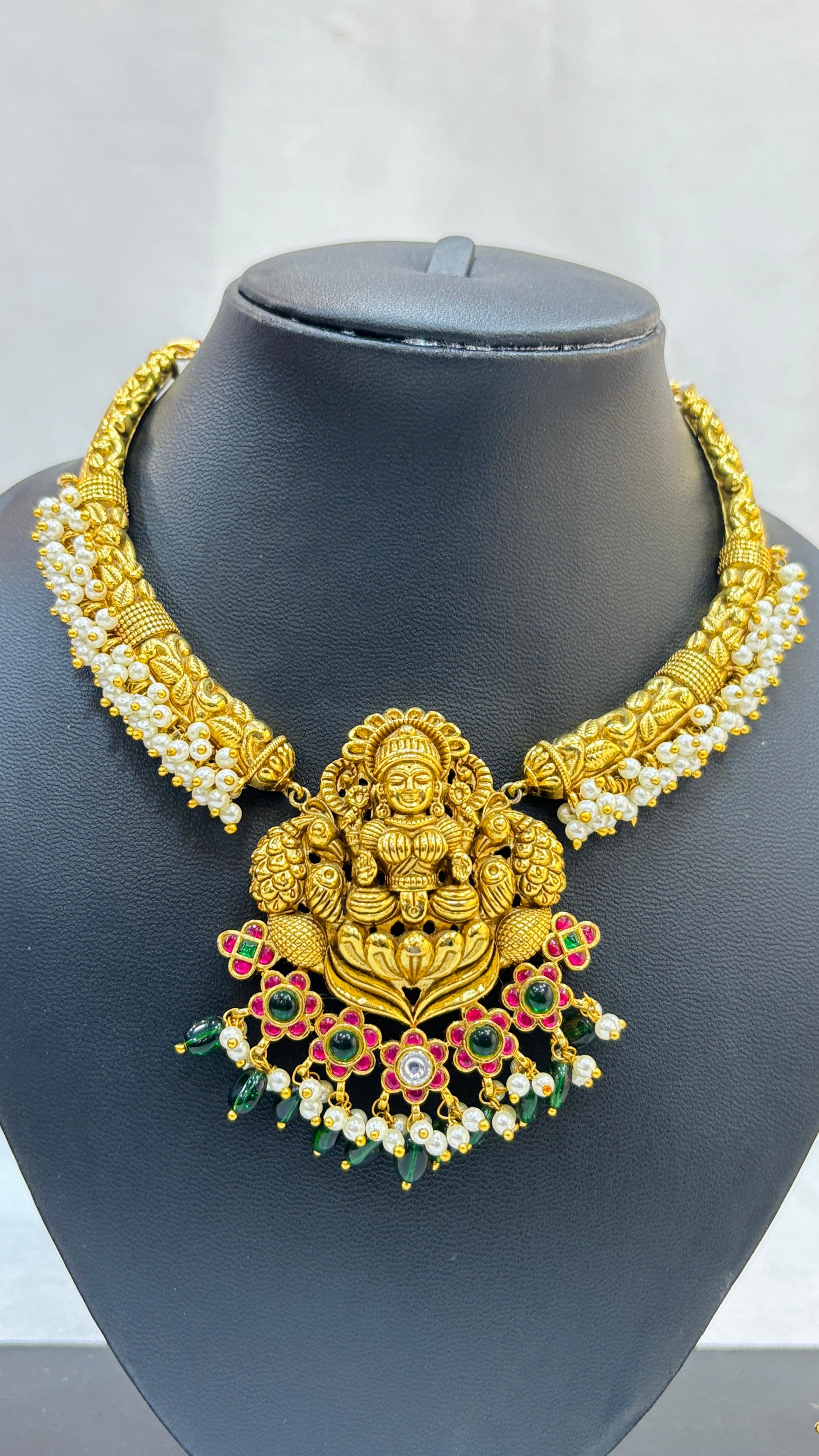 Gold necklace with a deity figure pendant on a mannequin bust.
